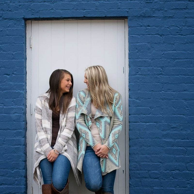 Two young women smiling at each other, wearing cold clothes