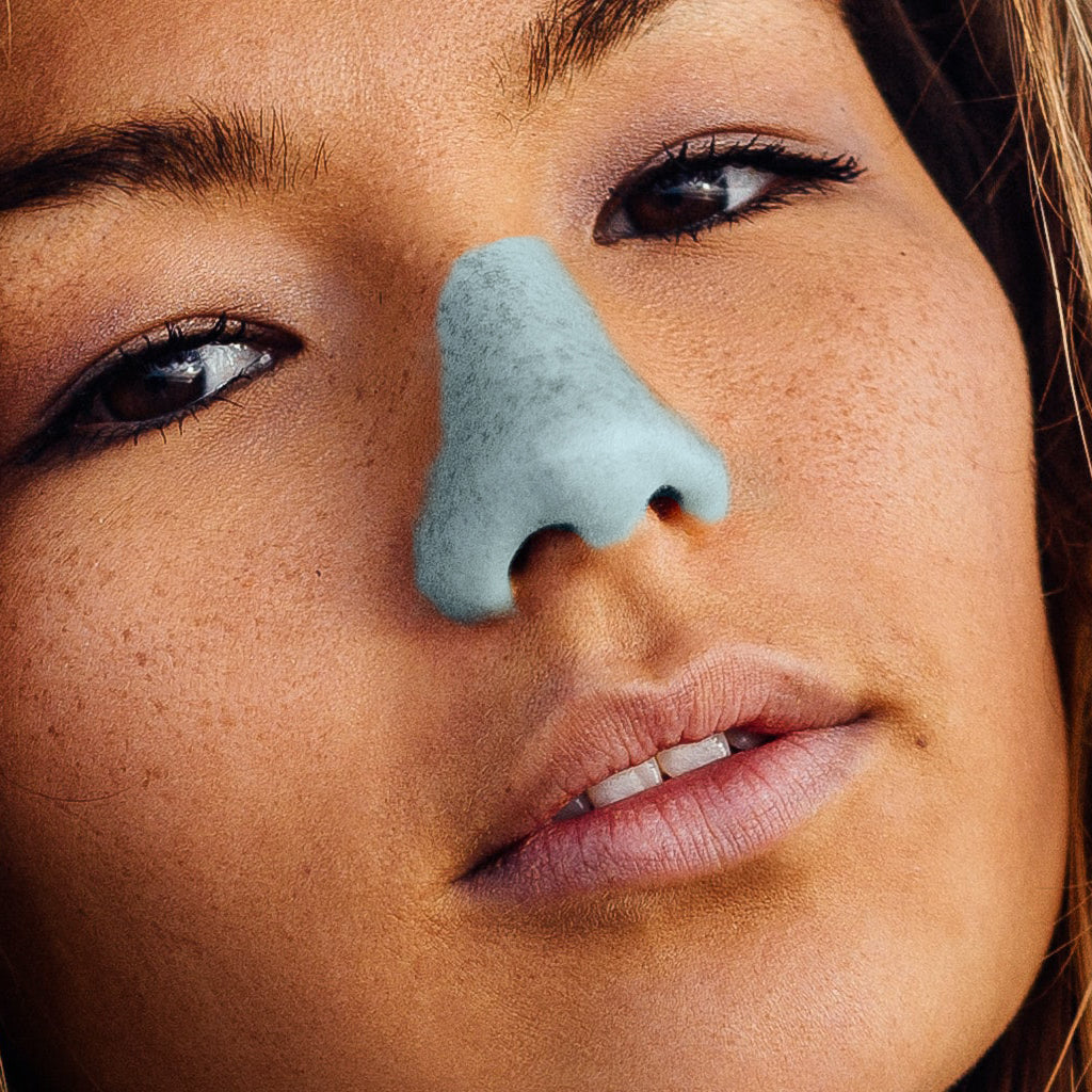 Woman using blue Noz sunscreen in her nose