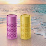 Load image into Gallery viewer, Bottles from Noz sunscreen in yellow and purple colors on the beach
